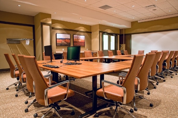 An image of a meeting room with a number of chairs around a rectangle table