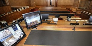 An image of a meeting room with 2 monitors on a desk receiving a remote hearing call