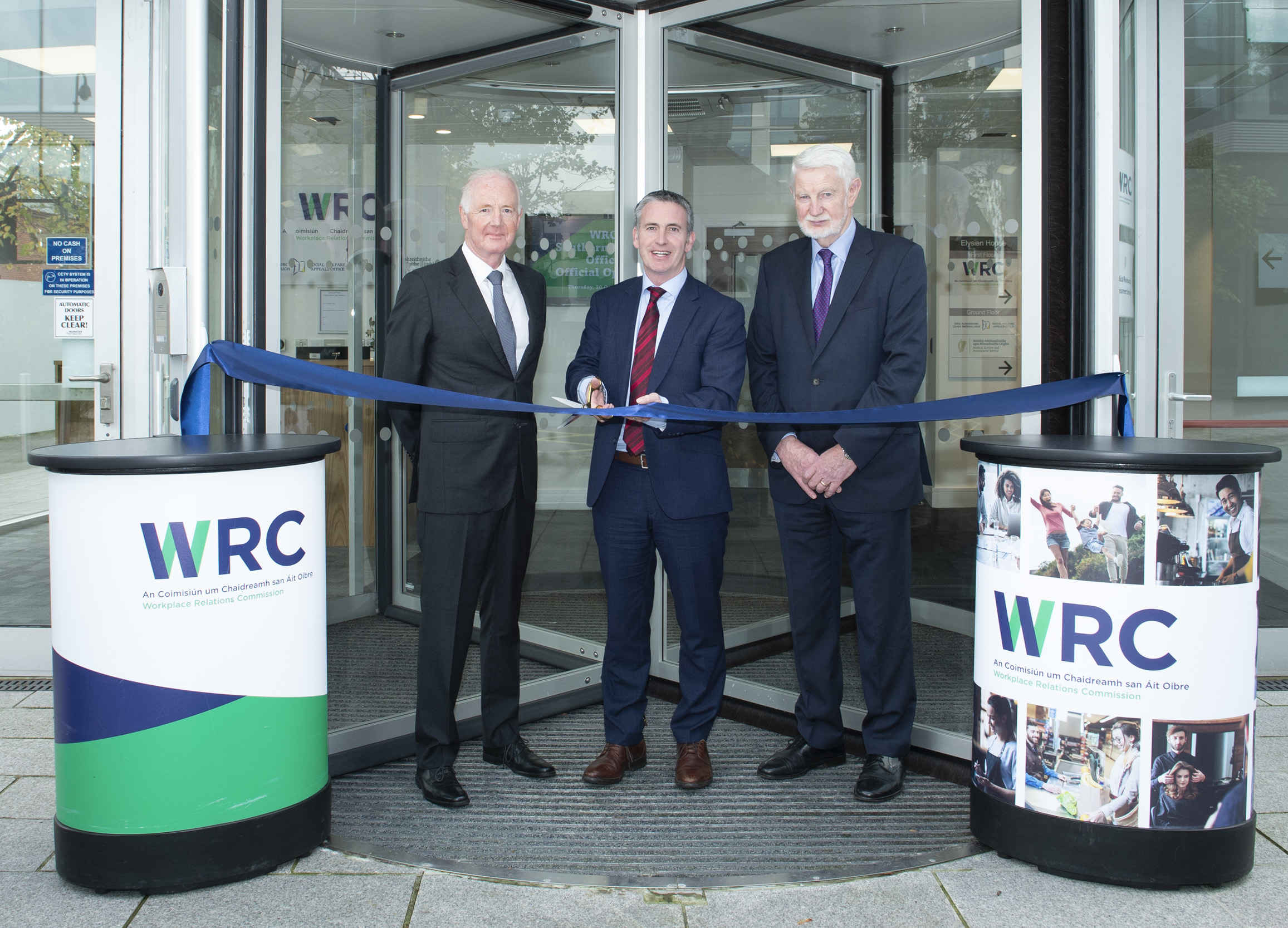 3 males cutting a ribbon to open the WRC Cork office
